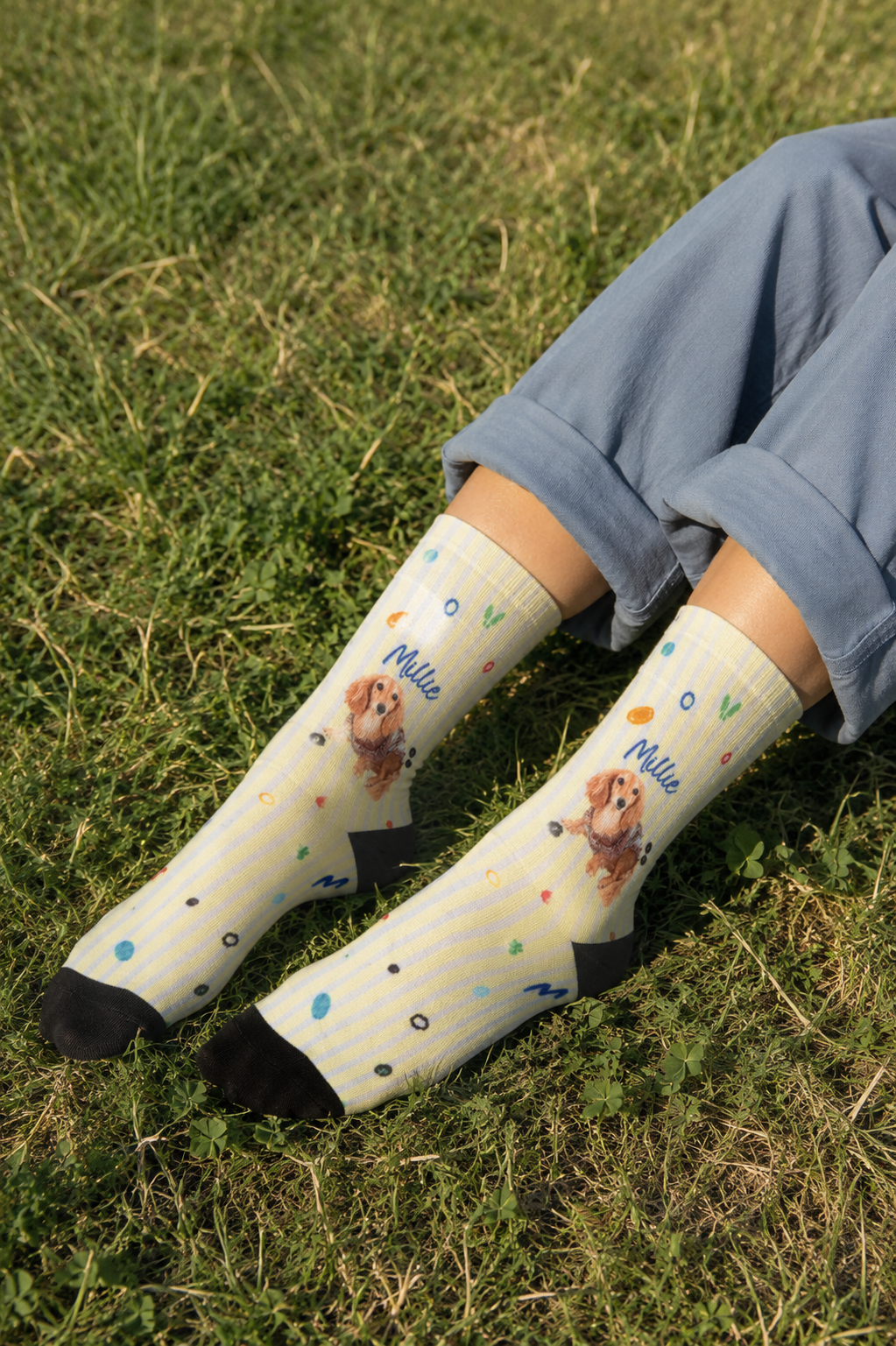 Cream pinstriped crew socks worn on grass, printed with a small dog and the name Millie