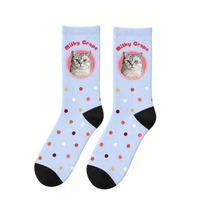 Pair of pale blue confetti-dot crew socks laid flat, showing a cat's face in a pink circle with the name above